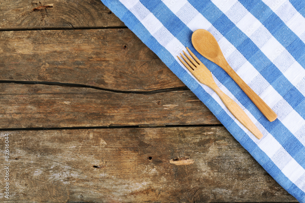 Checkered napkin with spoon and fork on wooden table background