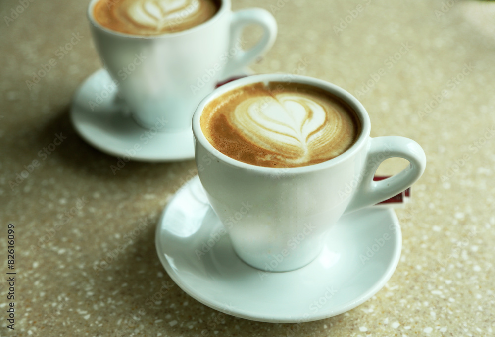 Cups of cappuccino with heart on foam on table in cafe Cups of cappuccino with heart on foam on table in cafe