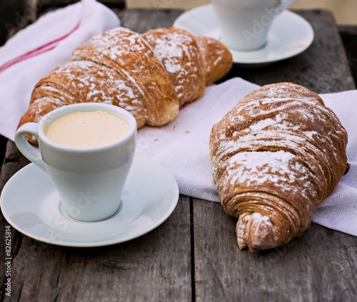 A cup of coffee "espresso" and croissant on the wooden table.
