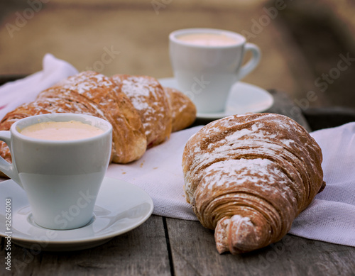 A cup of coffee "espresso" and croissant on the wooden table. 