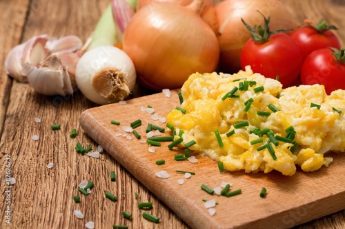 Portion of scrambled eggs with herbs on chopping board