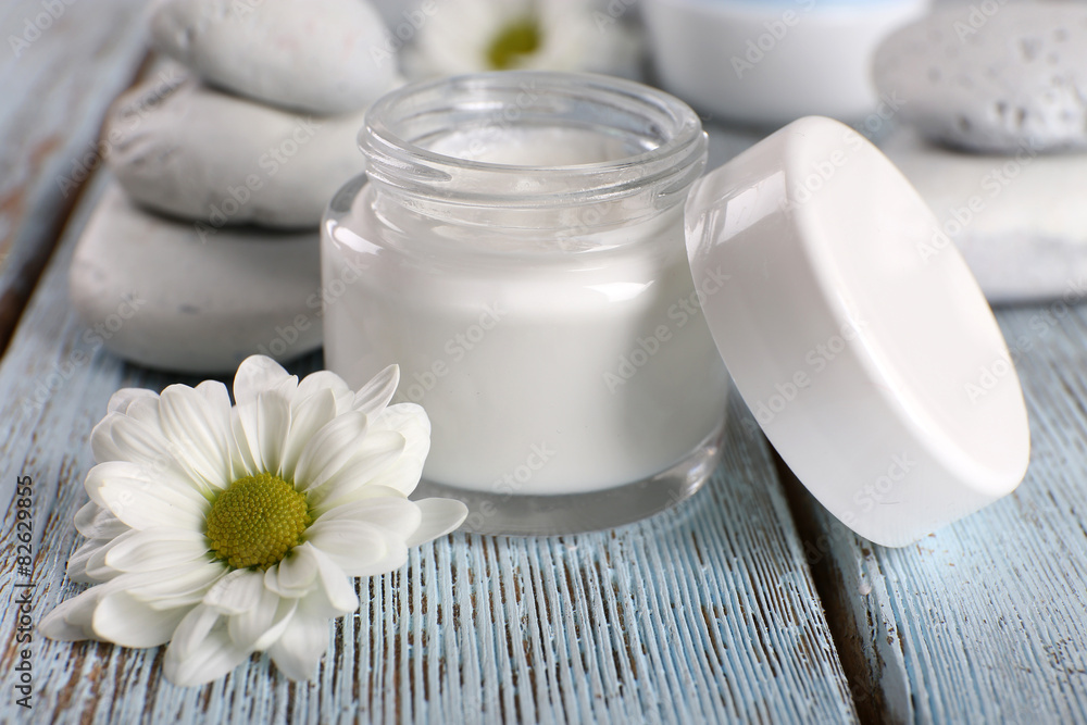 Cosmetic cream with flowers and spa stones on wooden background Cosmetic cream with flowers and spa stones on wooden background