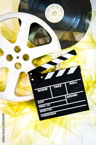 Movie clapper on 35 mm cinema reels unrolled yellow filmstrip