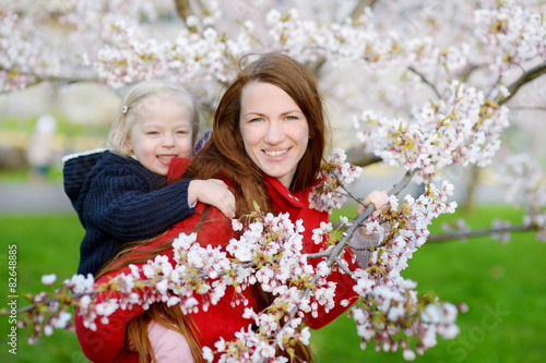 Mother and her child in blooming cherry garden