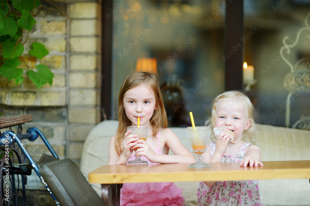 Two sisters drinking juice and eating pastries Two sisters drinking juice and eating pastries