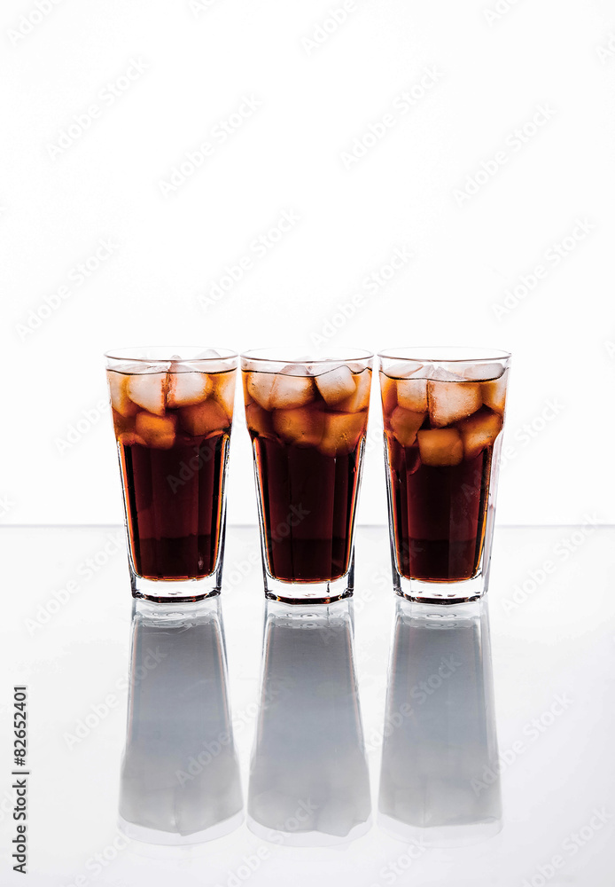 three glasses of cola and ice on a white background. soft drinks three glasses of cola and ice on a white background. soft drinks