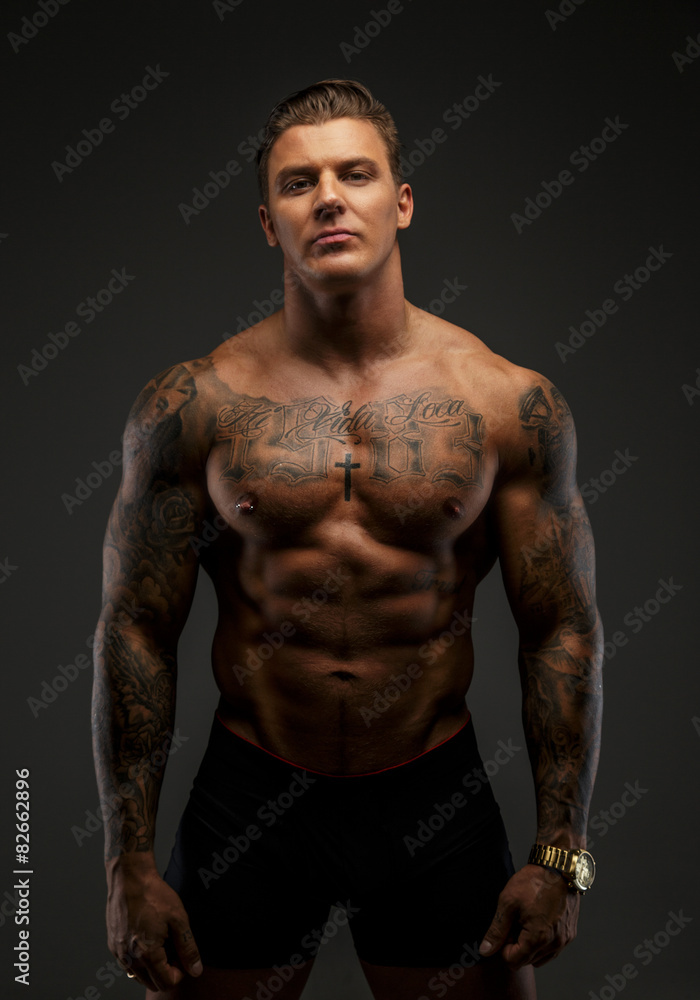 Fototapeta premium Muscular man with tattooes in deep shadows