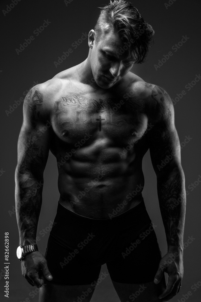 Muscular man with tattooes in deep shadows Muscular man with tattooes in deep shadows
