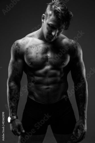 Muscular man with tattooes in deep shadows