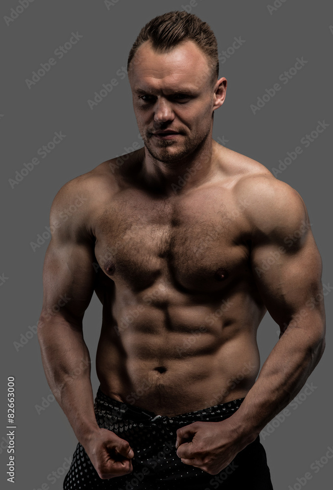 Muscular man posing in studio on grey background Muscular man posing in studio on grey background