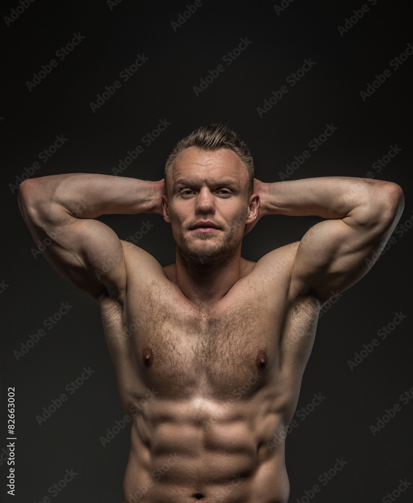 Muscular man posing in studio on grey background