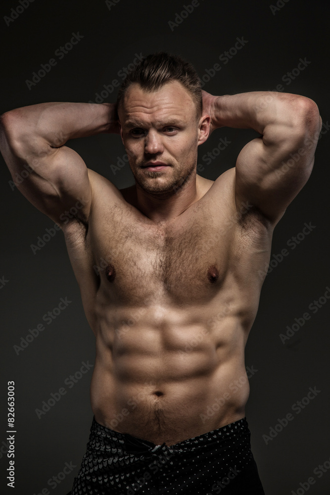 Muscular man posing in studio on grey background Muscular man posing in studio on grey background