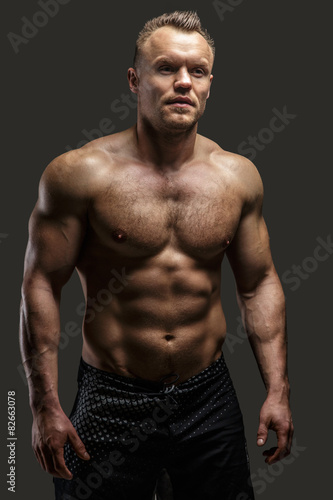 Muscular man posing in studio on grey background