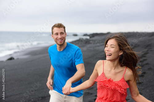 Happy couple laughing together walking on beach