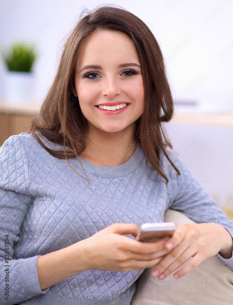Pretty girl using her smartphone on couch at home in the living Pretty girl using her smartphone on couch at home in the living