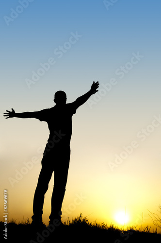 silhouette man arms outstretched to the side at sunset
