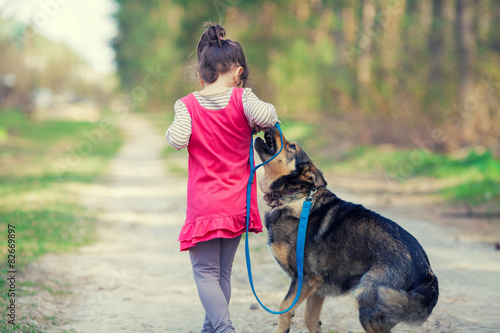 Little girl playing with dog in the village back to camera photo