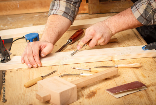 Closeup of a carpenter working with a chisel and carving tools