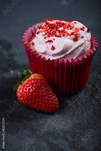 Strawberry cupkace decorated with icing on dark background photo