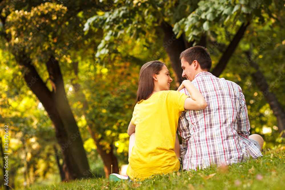 Fototapeta premium Rearview of a young couple sitting in park.