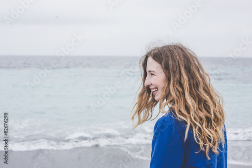 young blonde curly girl smiling having fun calm sea blue skies