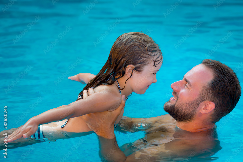 Child and father playing in swimming pool