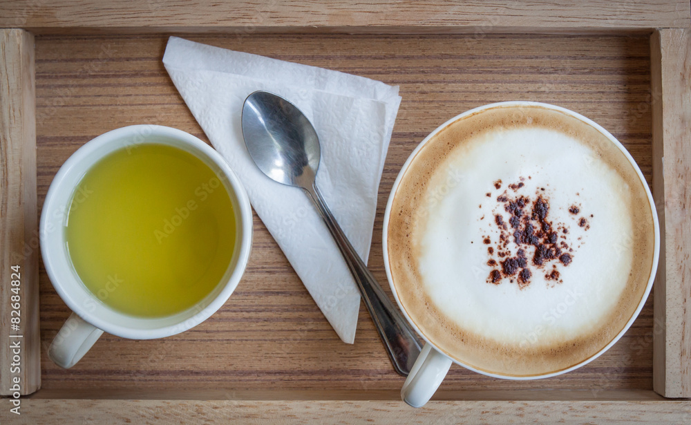Cappuccino and hot green tea and a spoon on a wooden tray. Cappuccino and hot green tea and a spoon on a wooden tray.