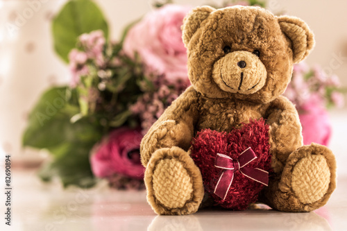 Hab Dich lieb – Teddybär mit Herz und Blumen im Hintergrund photo