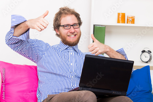 Happy man shows OK sign in front of a computer