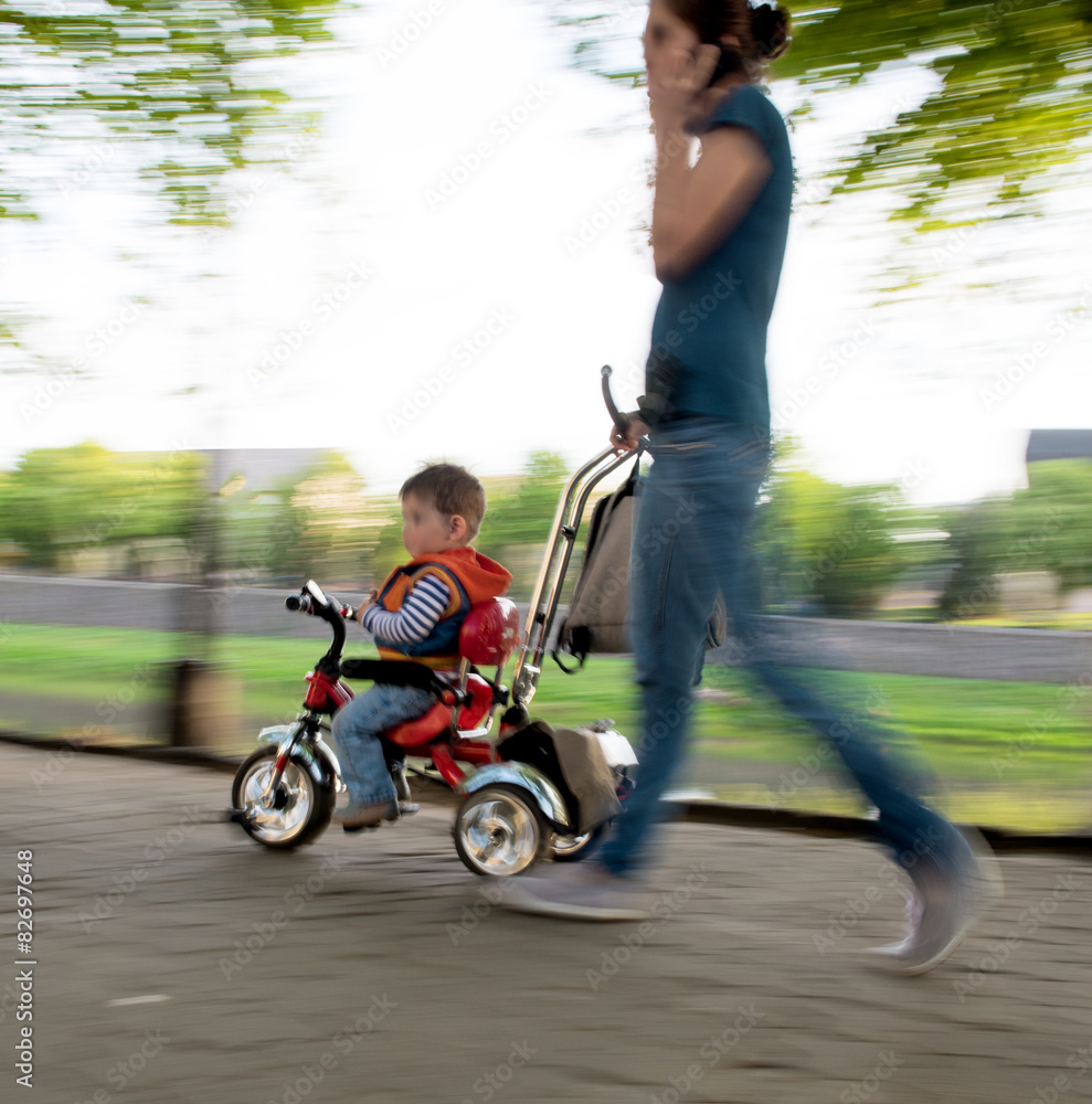 Mother pushing little bicycle with son Mother pushing little bicycle with son