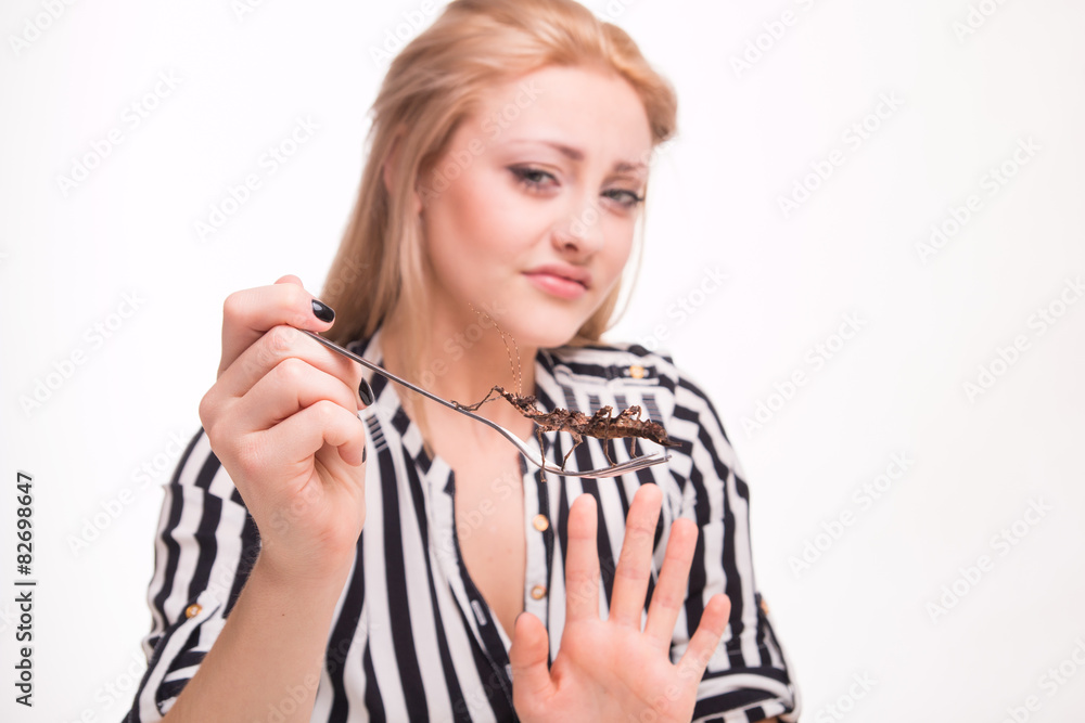 Disgusted woman eating insects with a fork in a restaurant