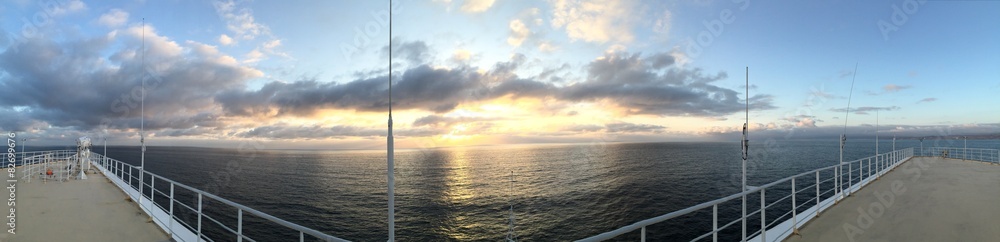 Panorama of sunset over ocean from bow and deck of oceanliner.