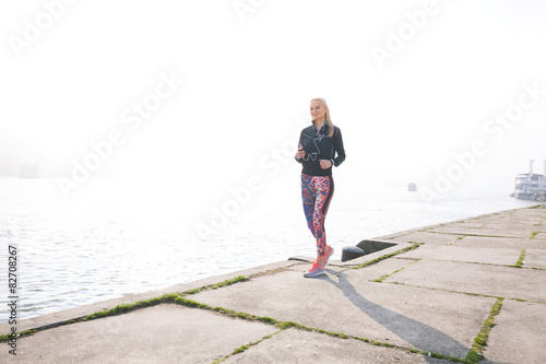 Attractive young woman jogging by the river on the morning mist