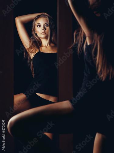 Beautiful young woman looking into a mirror at herself