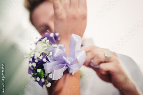 brides hand putting the boutonniere flower on groom