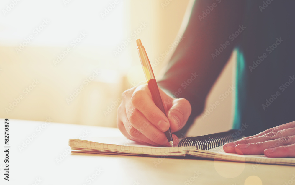 female hands with pen writing on notebook - obrazy, fototapety, plakaty 