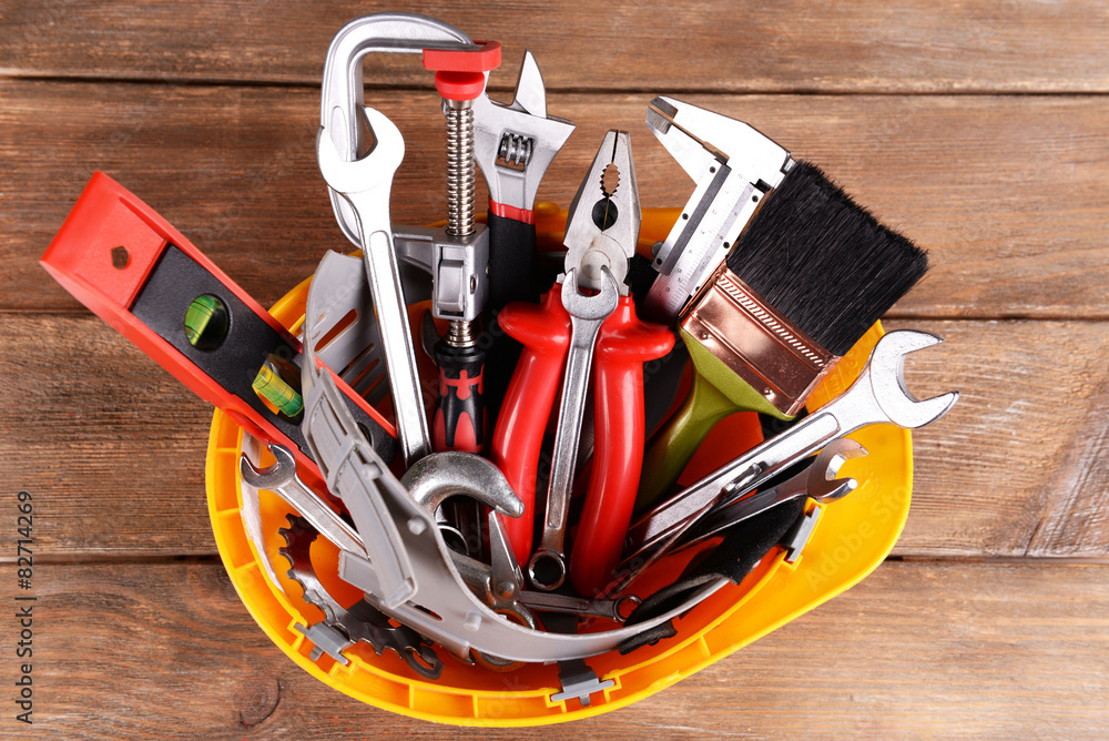 Construction tools in helmet on wooden background