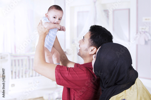 Parents lifting up their baby in bedroom