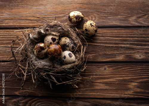 Quail eggs in the nest on a wooden board.