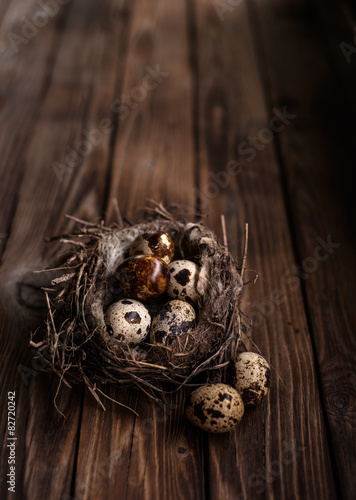 Quail eggs in the nest on a wooden board.