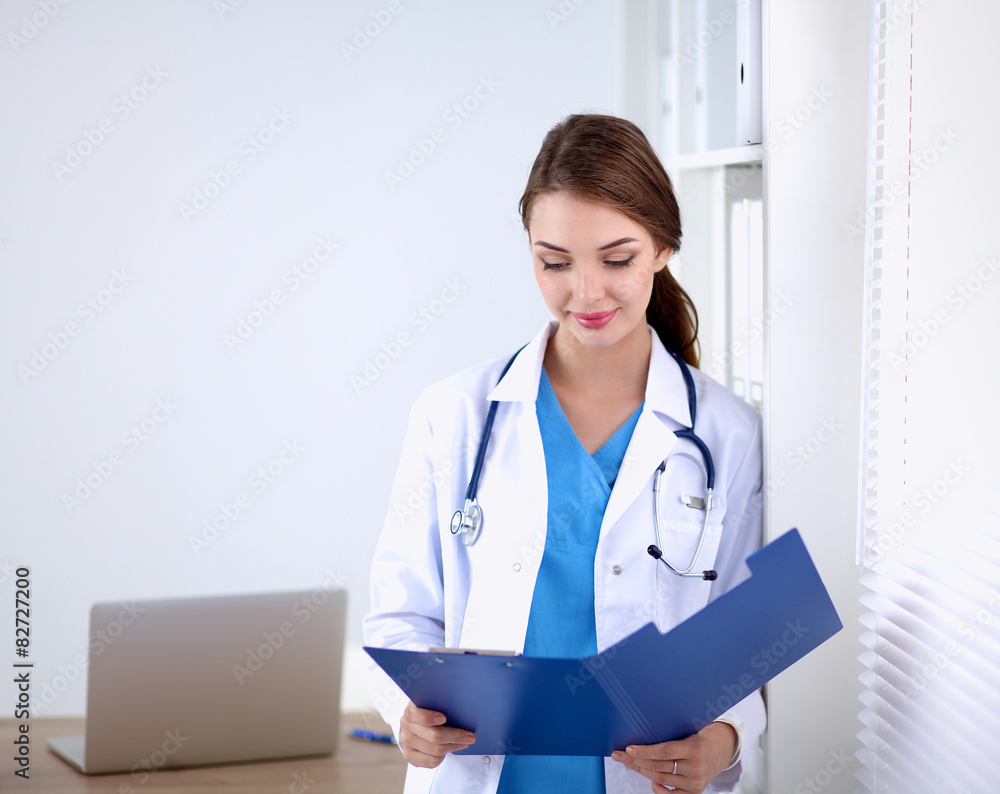 Woman doctor is standing near window with crossed arms,isolated Woman doctor is standing near window with crossed arms,isolated