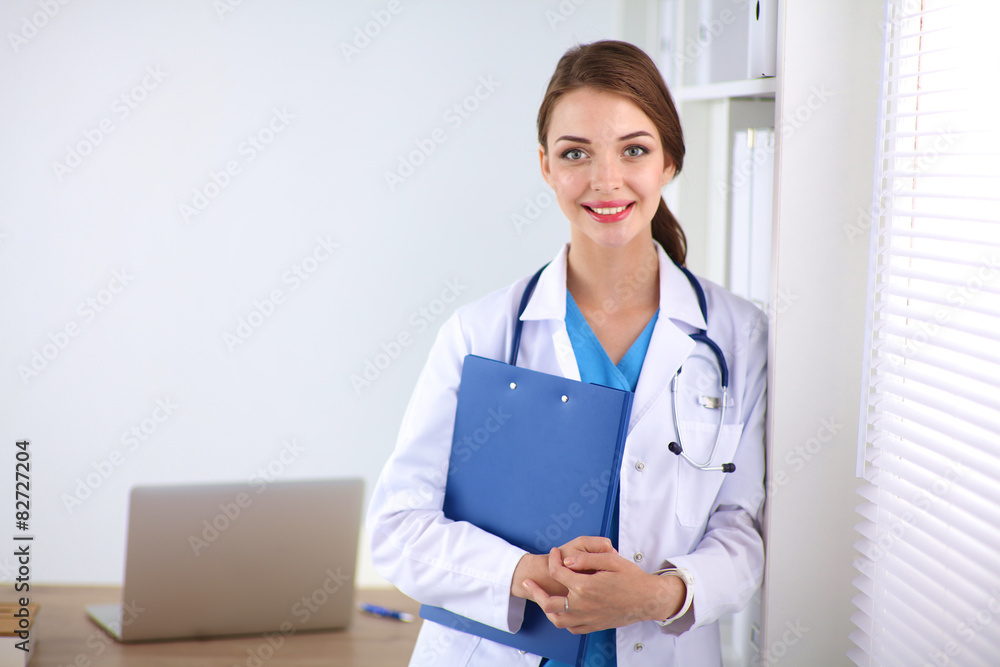 Woman doctor is standing near window with crossed arms,isolated Woman doctor is standing near window with crossed arms,isolated
