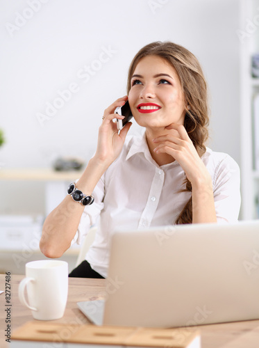 Young businesswoman sitting and talking on phone