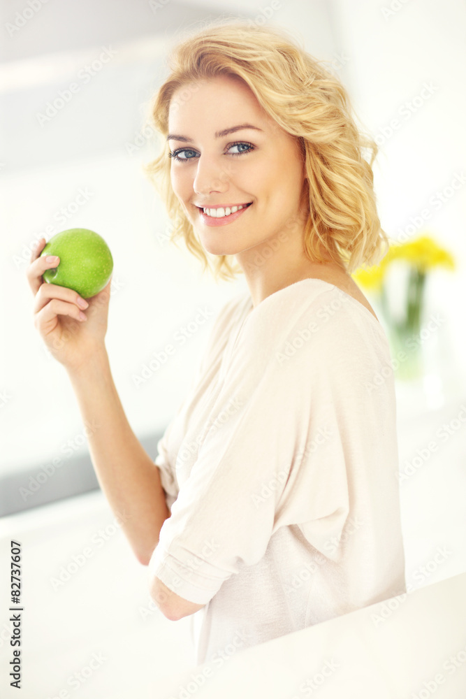 Young woman eating apple in the kitchen Young woman eating apple in the kitchen