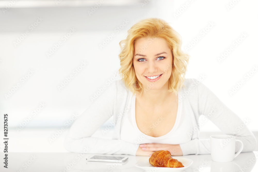 Young woman with smartphone in the kitchen Young woman with smartphone in the kitchen