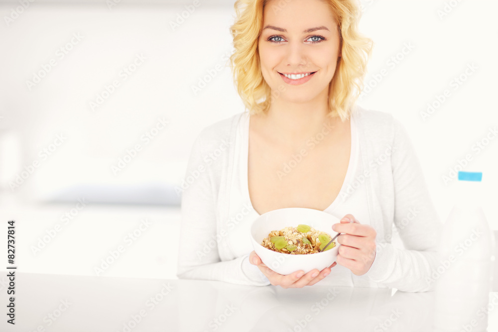 Young woman eating cereal in the kitchen
