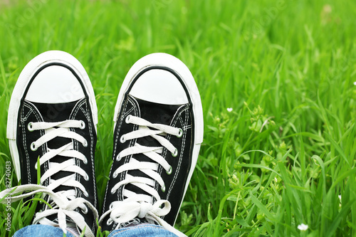 Female feet in gumshoes on green grass background