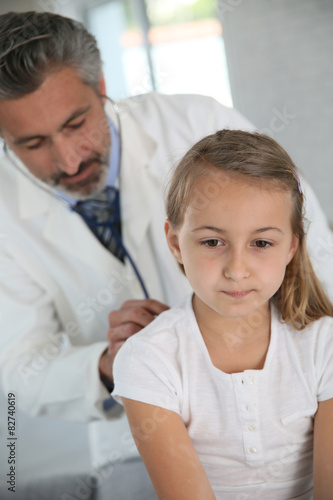 Doctor examining young girl with stethoscope