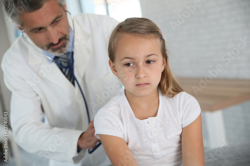Doctor examining young girl with stethoscope