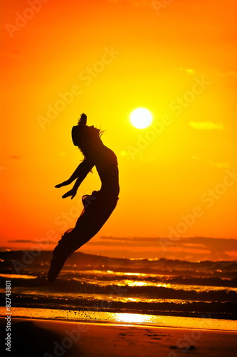 young woman jumping on the beach in summer evening